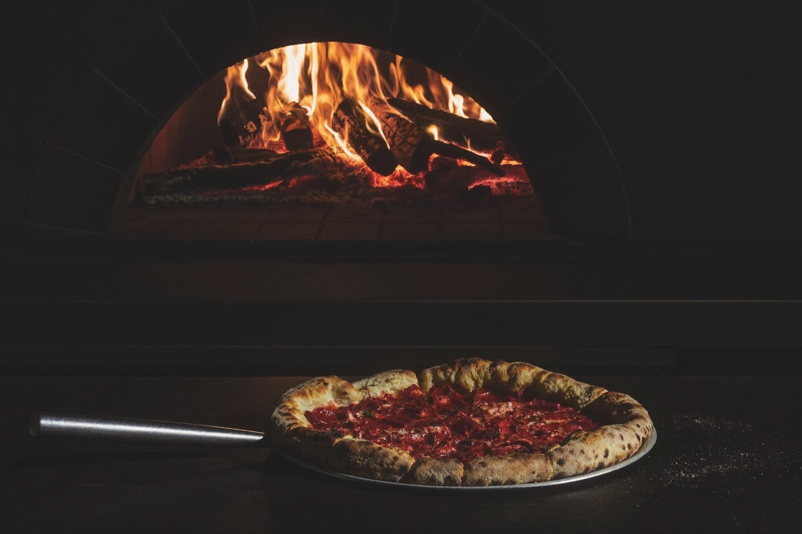 Wood-fired pizza in front of glowing open flames
